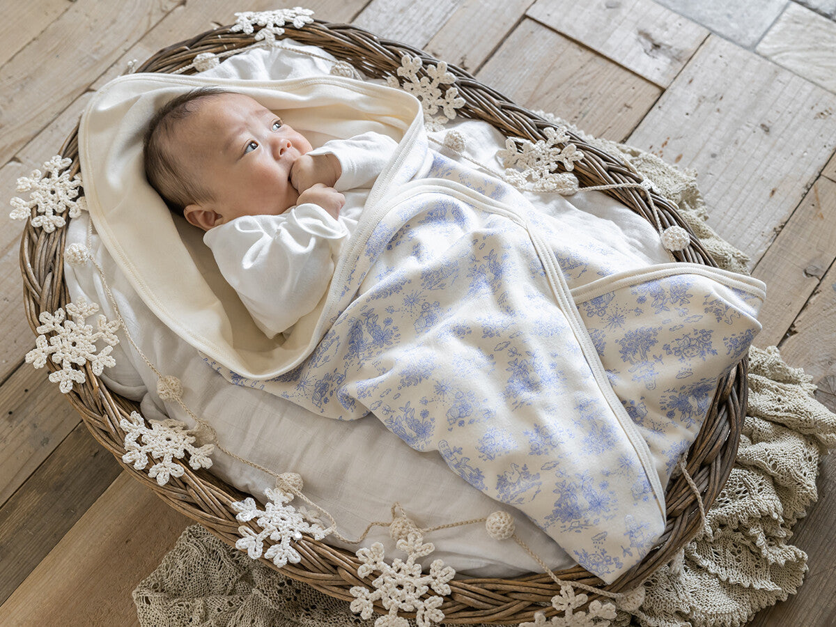 フレンチガーデン柄のブランケットに包まれた新生児